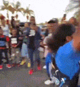 a blurred image of a crowd of people including a boy in a blue shirt