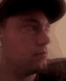 a close up of a man 's face wearing a hat and making a funny face .
