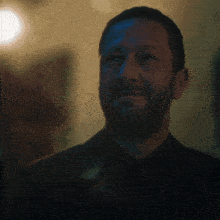 a man with a beard is wearing a black suit and black tie