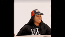 a woman in a white t-shirt is sitting at a table with her hands folded and talking to another woman .