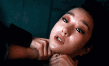 a close up of a woman 's face with a hand on her neck