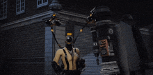 a man in a suit is standing in front of a building with a robotic device attached to him