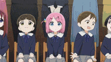 a group of children are sitting in a row and one of them has pink hair