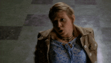 a woman in a tan jacket is holding her hands out