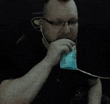a man wearing glasses is drinking from a plastic cup .