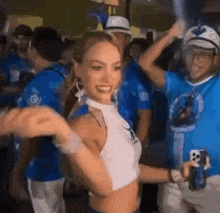 a woman in a crop top is dancing in a crowd of people at a party .