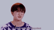a young man wearing glasses and a purple tie dye sweater is talking into a microphone .