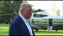 a man in a blue suit stands in front of a united helicopter