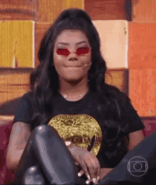 a woman wearing sunglasses is sitting on a couch .