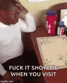 a man is sitting at a desk with his hand on his forehead and says " fuck it show me when you visit " .