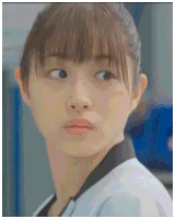a close up of a woman 's face with a ponytail and bangs
