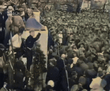 a crowd of people are gathered in front of a sign that says 24ack