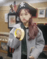 a girl wearing a pirate hat is holding a banana in her hand