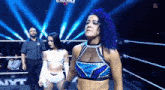 two women are standing in a wrestling ring with a referee .