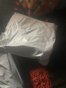 a white plastic bag is laying on top of a red and black blanket