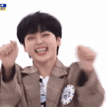 a young man in a suit is making a funny face while holding his fists in the air .