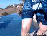 a man in blue shorts is standing in front of a swimming pool with the words subscribers ( 5 ) on the bottom