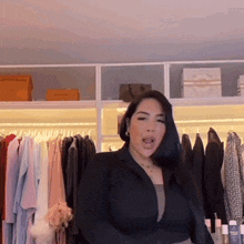a woman in a black jacket is standing in front of a closet