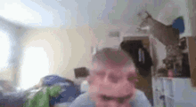a blurry picture of a man making a funny face in a room .