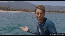 a man in a wetsuit is standing in the water .