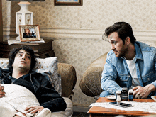 two men are sitting at a table with bottles of pills