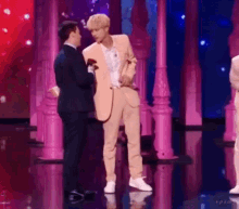 a man in a tan suit is standing next to another man on a stage .