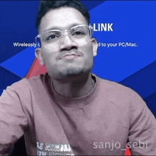 a man wearing glasses and a pink shirt with the name sanjo sebi on it