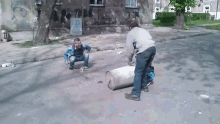 a man squatting down next to a barrel with the letter r on the wall