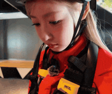 a woman wearing a red jacket and a yellow petzl badge
