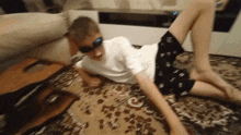 a young boy wearing sunglasses is laying on the floor with his legs crossed