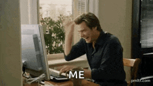 a man is sitting at a desk in front of a computer with a cup of coffee .
