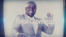 a man in a suit and tie waves in front of a screen that says " take control "