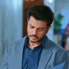 a man in a suit and blue shirt looks down