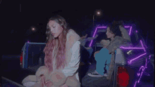 a girl with pink hair is sitting in the back of a truck .