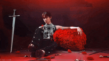 a woman sits on a red ball of roses with a sword