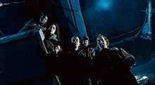 a group of people standing next to each other in a dark room looking up at the ceiling .