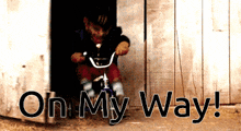 a boy riding a bike in a doorway with the words on my way behind him