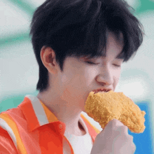 a young man eating a piece of fried chicken