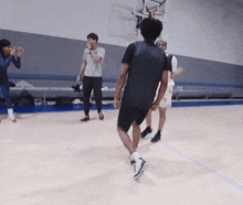 a group of people are playing basketball on a court and one of them is wearing a black shirt