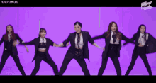 a group of women in suits are dancing in front of a purple background