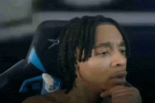 a man with dreadlocks is sitting in a chair with a scissors in his hair .