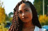 a close up of a woman 's face with braids and a necklace .