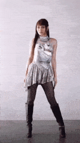 a woman is wearing a silver dress and black boots .