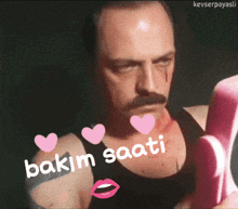 a man with a mustache is holding a pink object and the words " bakim saati " are on his chest