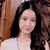 a woman with long black hair is wearing a white tank top