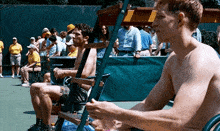 a shirtless man is sitting on a chair on a tennis court .