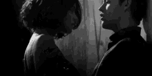 a man and a woman are kissing in a black and white photo . the woman is wearing a black dress .