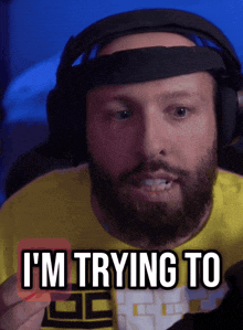 a man with a beard wearing headphones and a yellow shirt that says i 'm trying to