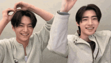 a couple of young men are standing next to each other and smiling .