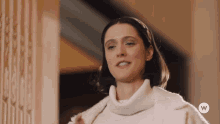 a woman wearing a white sweater and a white coat with the letter w on the bottom right